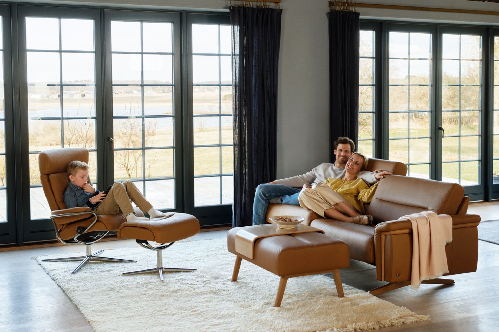 A couple sitting on a Stressless Stella Sofa and a Boy sitting on a Stressless Recliner