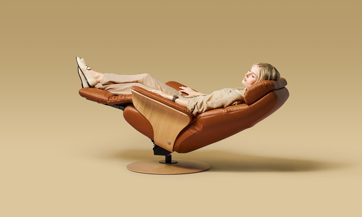 A person resting in the fully reclined Stressless Adam in cognac leather