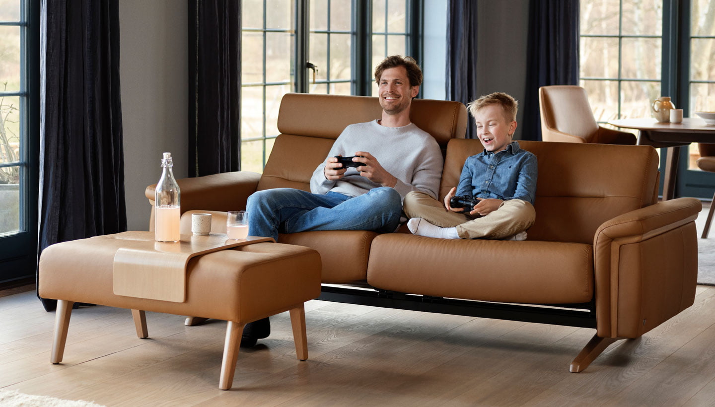 Father and son playing video games on Stressless Stella wood sofa