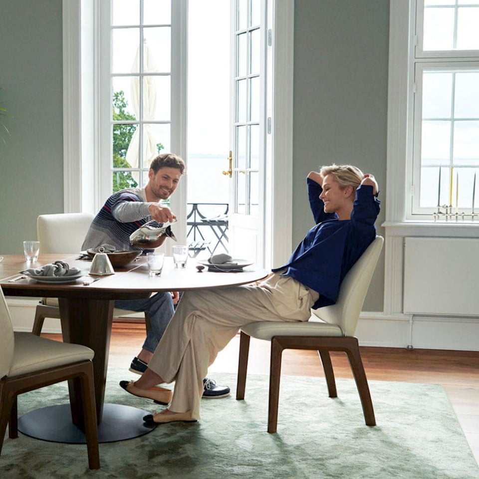 Couple eating breakfast, sitting at Stressless dining set up.