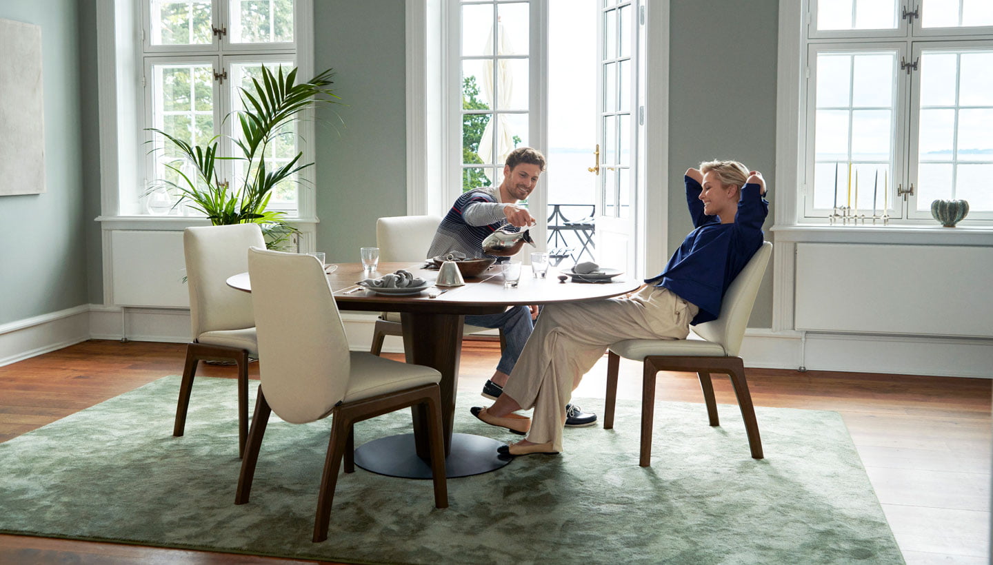 Couple eating breakfast, sitting at Stressless dining set up.