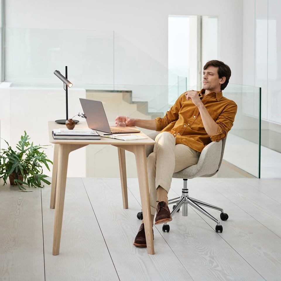 A man sitting in a Stressless® Bay Home office in front of a consol table